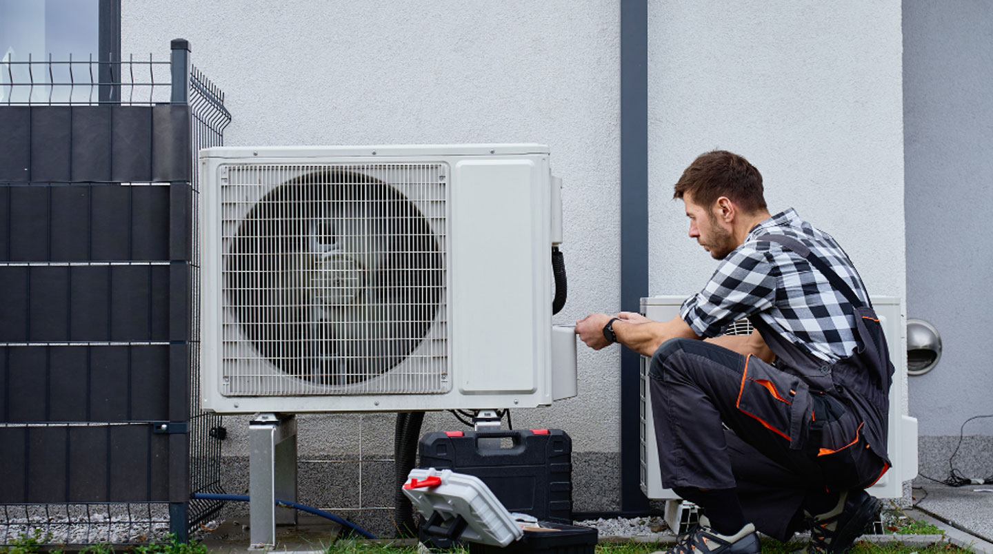 Technicien HVAC certifié installant une unité murale de thermopompe à l'intérieur d'une résidence québécoise, mains en train de connecter les conduites de réfrigérant avec outil de précision